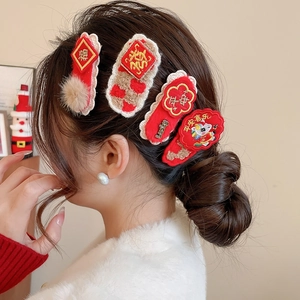 Detail of red and cream New Year hair clips with intricate embroidery and plush texture