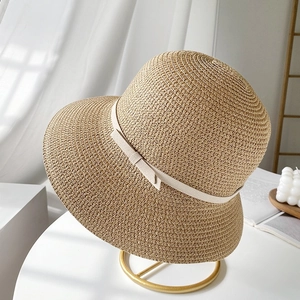 Japanese style woven straw sun hat for women with a delicate bow on a gold stand