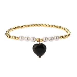 Detailed macro view of beaded bracelet with gold accents, white pearls and a black heart charm