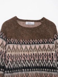 Close-up of the round neckline and fuzzy knit texture of a brown jacquard sweater