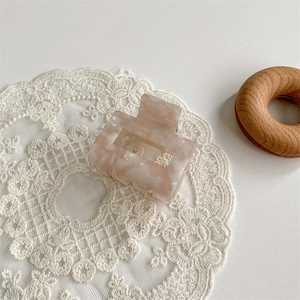 Detail of marble pattern acetate shark hair claw clip on white lace accessory mat