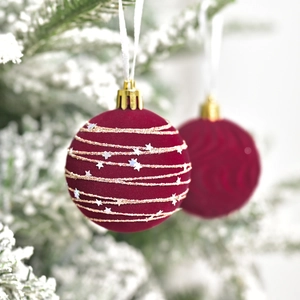 Velvet burgundy Christmas balls with gold lines and silver sequins on snowy tree branch