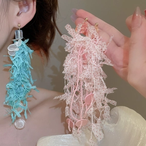 Close-up of asymmetrical blue and pink floral tassel earrings with shell resin details