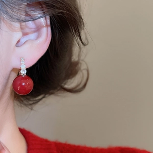 Macro detail of red zircon drop earring on model with elegant gold geometric setting