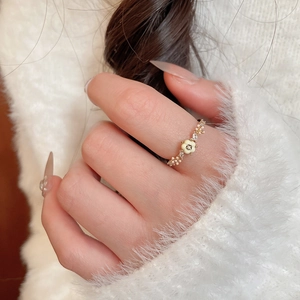 Gros plan d'une bague fleur dorée avec pétales blancs et cristaux sur un doigt
