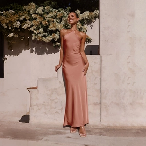 Detail of elegant backless satin maxi dress in sunset rose gold with halter neckline
