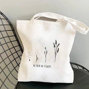 Detail of white canvas tote bag with 'NO RAIN NO FLOWERS' print and plant line art