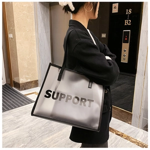 Detail of large frosted tote bag with black leather straps and Support print text