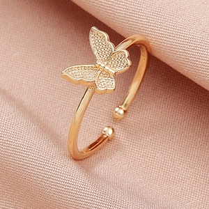 Macro shot of gold butterfly open ring with pave crystals on soft pink silk background