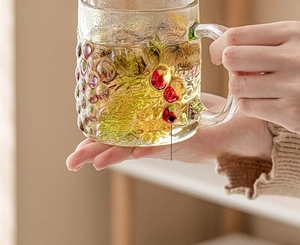 Detail of hand-painted glass mug with textured grape pattern and purple berry accents