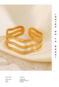 Macro detail of gold 3-layer wave ring featuring a hammered texture on silk background