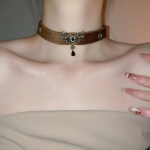 Close-up of vintage brown velvet choker with ornate metal pendant and black gemstones