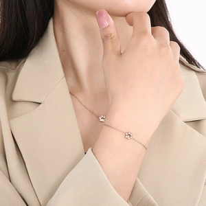 Detailed close-up of a rose gold flower bracelet on a wrist with minimalist design
