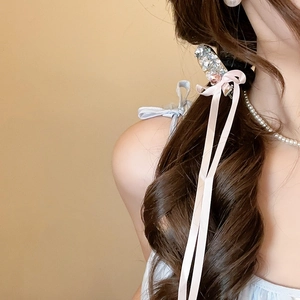 Detail view of rhinestone hair clip with elegant long pink ribbon streamers on wavy hair