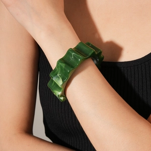 Detailed macro view of a wavy emerald resin bangle with marble texture on woman's wrist