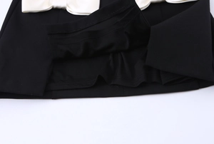 Detailed view of the elegant white satin bow on a sleeveless black dress fabric