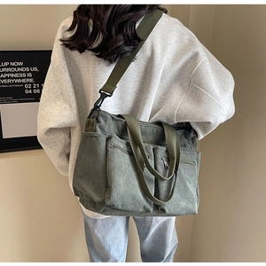 Detailed view of green corduroy crossbody bag featuring multiple functional zip pockets