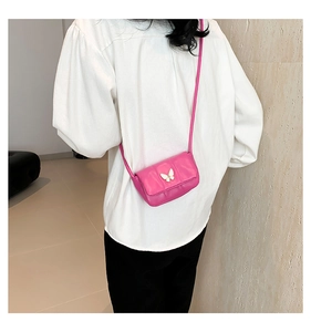 Détail d'un mini sac rose matelassé avec charme papillon doré et fine bandoulière