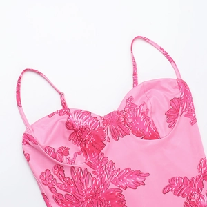 Nahaufnahme eines rosa Trägerkleids mit floralen Prägedetails und seidiger Textur