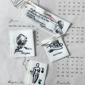 Artistic fabric embroidered brooch set with minimalist line portraits on white canvas