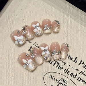 Macro detail of handmade press-on nails with 3D white flowers, pearls and cat-eye finish