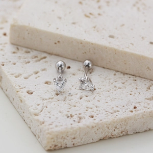 Detailed macro of S925 silver heart stud earrings with cubic zirconia on travertine stone