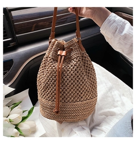 Detail of handwoven paper straw bucket bag with leather drawstring and shoulder strap