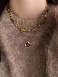 Close-up of double-layer gold tiger eye pendant necklace on a brown knit sweater
