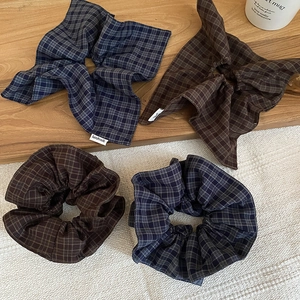 Detail of grid fabric scrunchies in blue and brown with handmade tag on wooden background