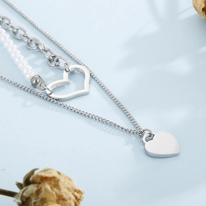 Detail of silver heart pendants on double-layered pearl and chain link necklace