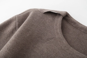 Detailed close-up of brown knit fabric texture on collar and shoulder of the cardigan