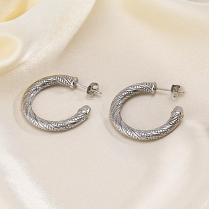 Silver twisted rope hoop earrings with ball ends on elegant beige silk fabric background