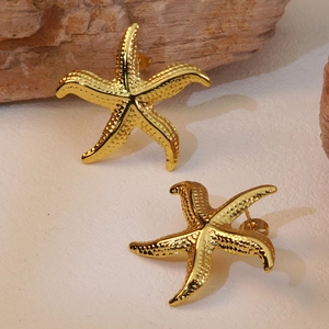 Textured gold starfish stud earrings in stainless steel on a natural stone background