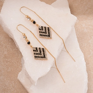 Detail of geometric rhombus tassel earrings with black and white rhinestones on stones