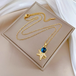Macro shot of gold astronaut pendant with sparkling zircon inlays on white silk