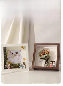 Detail of deep 3D shadow box frames with dried flowers and miniature wedding figurines