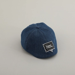 Dettaglio della coppola in denim blu con toppa Happy Faces e motivo a scacchi neri