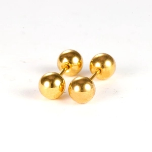 Macro shot of minimalist gold stainless steel screw ball stud earrings for cartilage piercing