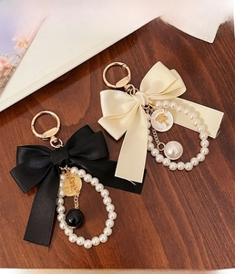 Detail of satin bow keychains with pearl strands and fashion gold-tone charms