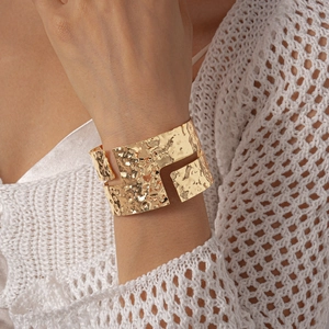Detail shot of golden cuff bracelet featuring irregular geometric cutouts and hammered texture