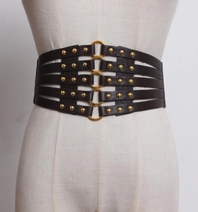 Detail of black faux crocodile leather belt with gold metal rings and stud accents
