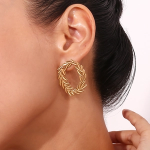 Detailed close-up of 18K gold-plated stainless steel laurel leaf hoop earrings on model