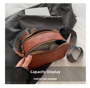 Detail view of brown vintage floral embossed shoulder bag with dual zipper and wide strap