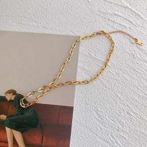 Collana chic a catena placcata oro 18k su un piedistallo bianco minimalista strutturato