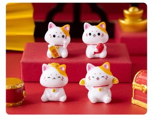 Set of four resin lucky cat figurines with fortune signs on a festive red background