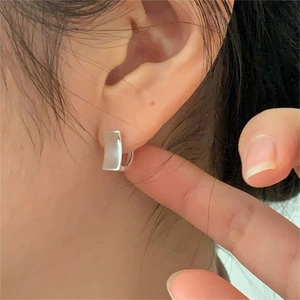 Close-up of minimalist silver geometric square earrings worn on a model's earlobe