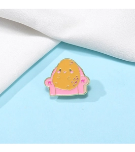 Détail de la broche en métal dessin animé pomme de terre jaune sur canapé rose