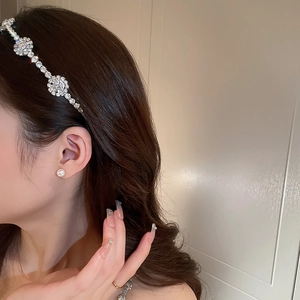 Dettaglio di un elegante cerchietto con strass a forma di foglia indossato sui capelli sani