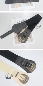 Detail of elastic waist belt with vintage gold buckle in black and beige colors
