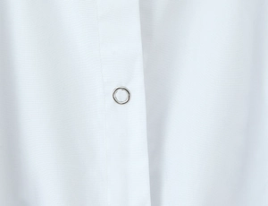 Macro detail of white fabric texture and silver circular metal buckle on puff sleeve shirt